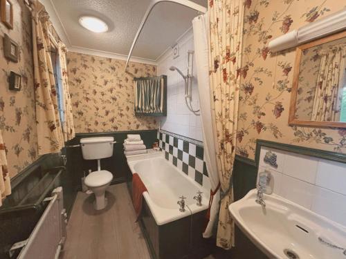 ein Badezimmer mit Toilette, Badewanne und Waschbecken in der Unterkunft Charming Lilac Cottage, Aldbrough, East Yorkshire in Aldbrough