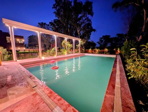 an infinity pool with a pergola and a swimming pool at Qila Hotel in Pipalsāna