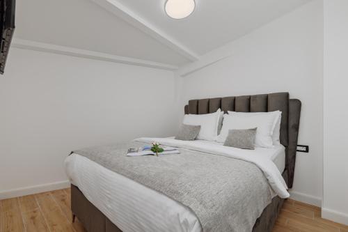 a white bedroom with a large bed with white pillows at Berge Apartments in Kotor