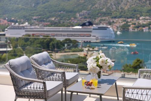 a balcony with chairs and a table with flowers on it at Berge Apartments in Kotor