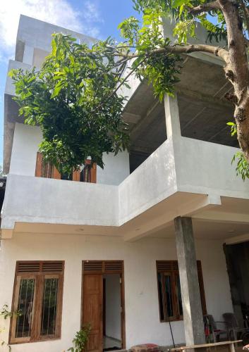 a white building with a tree in front of it at Casa Lashmika in Hikkaduwa