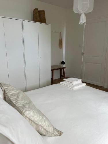 ein Schlafzimmer mit einem weißen Bett mit weißen Schränken und Büchern in der Unterkunft Le Petit Cottage - Appartement Centre-Ville & Plage in Concarneau