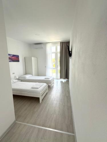 a white room with two beds and a window at Casa WEEK Dunare in Baziaş