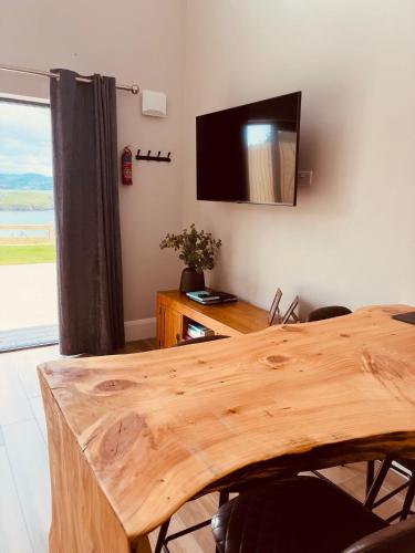 a room with a wooden table and a television on the wall at Teach Máire, Downings in Downings