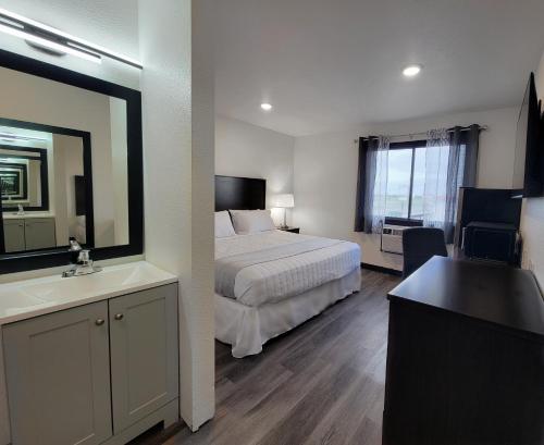 a bedroom with a bed and a sink and a mirror at The Suite Inn Minot in Minot