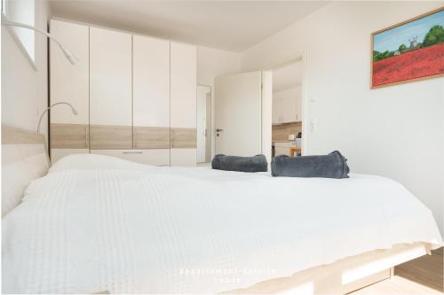 1 dormitorio blanco con 1 cama blanca grande y 2 sillas en Ferienwohnung Fördekönig, en Laboe