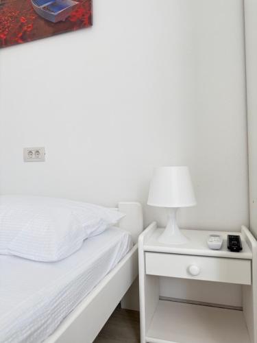 a white bed with a lamp on a night stand at Casa WEEK Dunare in Baziaş