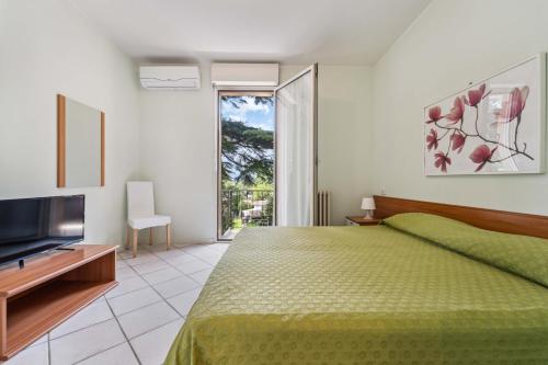 a bedroom with a green bed and a television at Green Village Accommodations in Colico