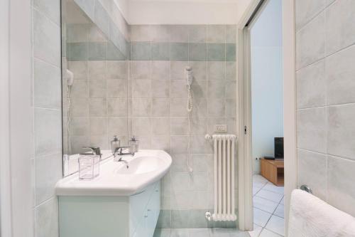 a white bathroom with a sink and a radiator at Green Village Accommodations in Colico