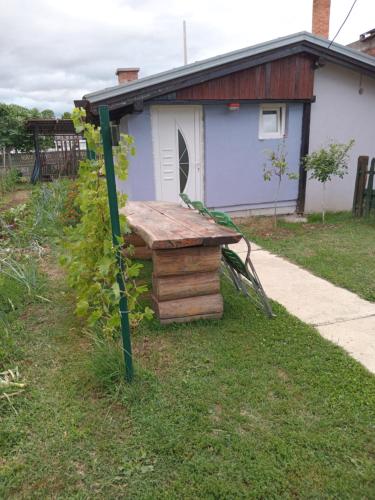 a wooden bench sitting in the grass in front of a house at Apartmani Primus in Bosanska Gradiška
