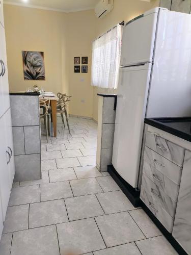 a kitchen with a white refrigerator and a table at CASA OT ESTRELA - Climatização, churrasqueira e piscina in Três Lagoas