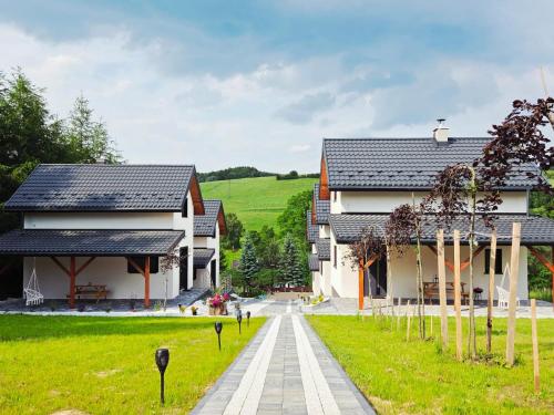 two houses and a walkway next to a house at Domki w Bieszczadach Kuźmina in Kuźmina