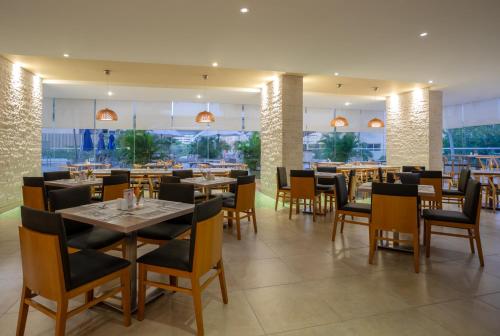 a dining room with tables and chairs in a restaurant at Mercure Santa Marta Emile in Santa Marta