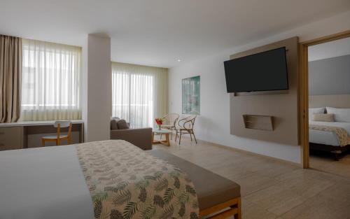 a hotel room with a bed and a flat screen tv at Mercure Santa Marta Emile in Santa Marta