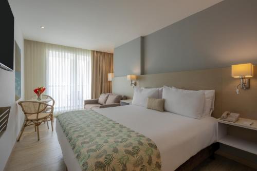 a hotel room with a large bed and a chair at Mercure Santa Marta Emile in Santa Marta