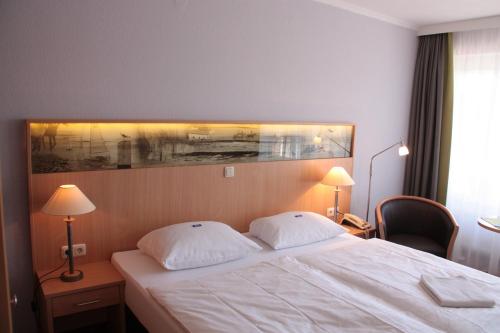 a hotel room with a bed with two pillows at Hotel Spiekeroog in Spiekeroog