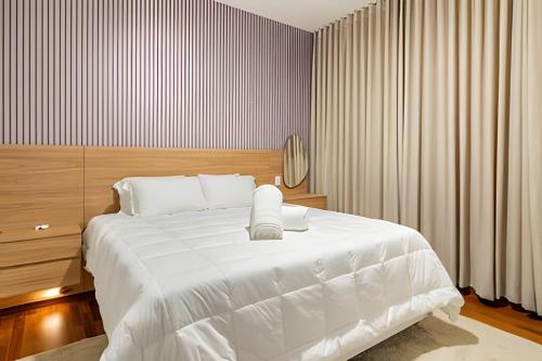 a bedroom with a large white bed and a mirror at Flat Belverede in Belo Horizonte