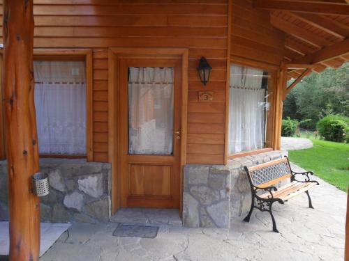 a wooden front door of a house with a bench at Apart Hotel del Pellin in San Martín de los Andes