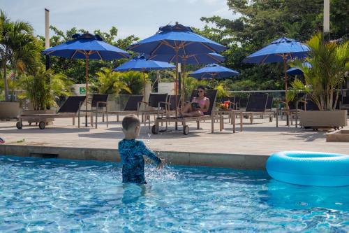 a young boy standing in the water in a swimming pool at Mercure Santa Marta Emile in Santa Marta