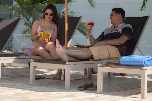 a man and woman sitting in a chair on the beach at Mercure Santa Marta Emile in Santa Marta