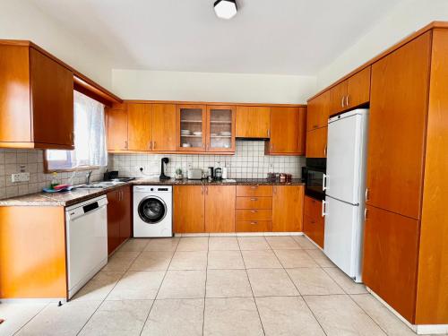 a kitchen with wooden cabinets and a white refrigerator at STAY Tranquility Cove in Larnaka