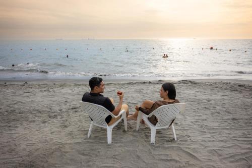 a man and woman sitting in chairs on the beach at Mercure Santa Marta Emile in Santa Marta