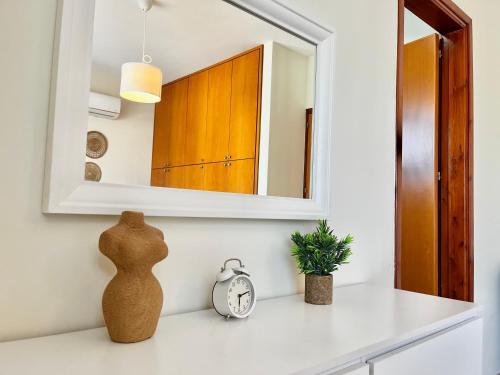 a mirror on a wall above a counter with a clock at STAY Tranquility Cove in Larnaka