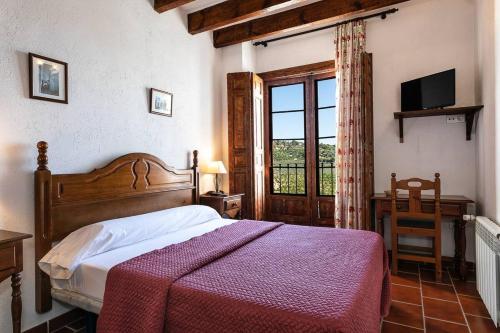 a bedroom with a bed and a window and a television at Casa Rural Del Rio in Alozaina