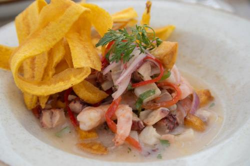 a plate of food with shrimp and potato chips at Mercure Santa Marta Emile in Santa Marta