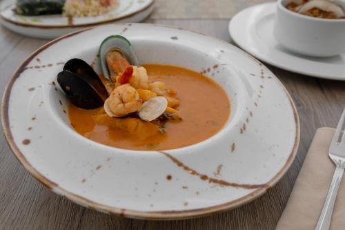 a bowl of soup with shrimp and mussels on a table at Mercure Santa Marta Emile in Santa Marta