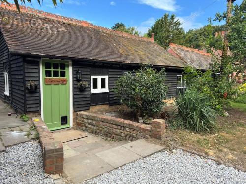 a small house with a green door in a yard at A charming cottage nestled in a peaceful woodland in Byfleet