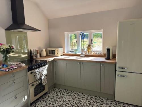a kitchen with white cabinets and a stove top oven at A charming cottage nestled in a peaceful woodland in Byfleet