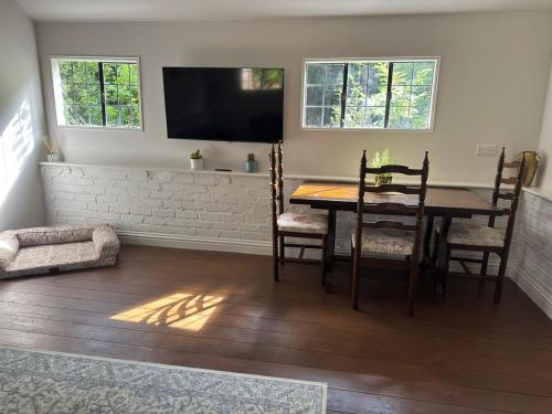 a dining room with a table and chairs and a television at A charming cottage nestled in a peaceful woodland in Byfleet