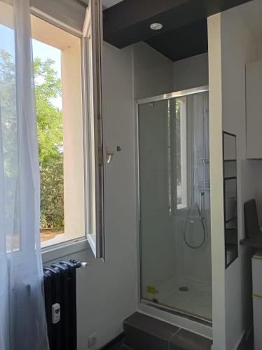 La salle de bains est pourvue d'une douche et d'une fenêtre. dans l'établissement Studio proche de Paris, à Saint-Cloud
