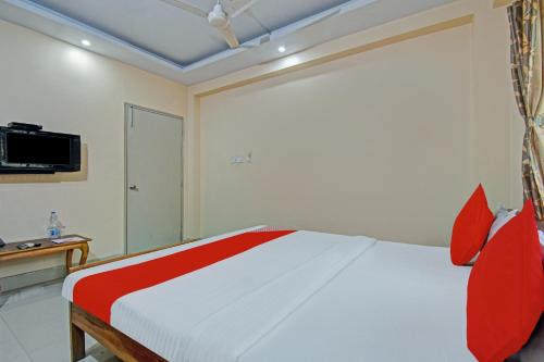a bedroom with a bed with red pillows and a tv at Hotel O Sai City inn in Jādabpur
