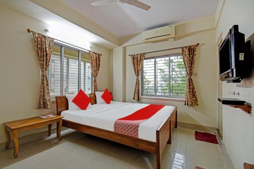 a bedroom with a bed with red pillows and a tv at Hotel O Sai City inn in Jādabpur