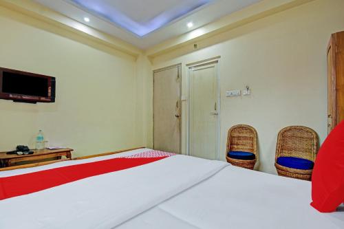 a bedroom with a bed with two chairs and a television at Hotel O Sai City inn in Jādabpur