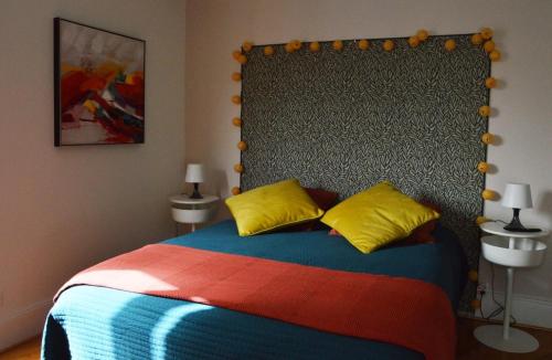 ein Schlafzimmer mit einem großen Bett mit gelben und roten Kissen in der Unterkunft Magnifique studio au centre historique in Mulhouse