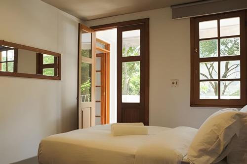 a bedroom with a bed and two windows at Natureza e Sossego em BH in Macacos