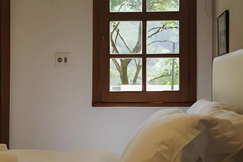 a bedroom with a window and a bed with white sheets at Natureza e Sossego em BH in Macacos