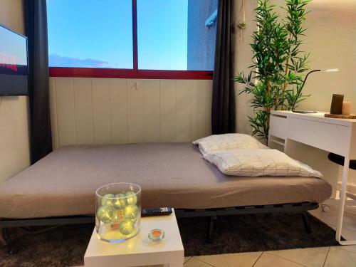 - un petit lit dans une chambre avec une table et une fenêtre dans l'établissement Studio climatisé Avenue 83 à 10mn de Hyères et de Toulon, à La Valette-du-Var