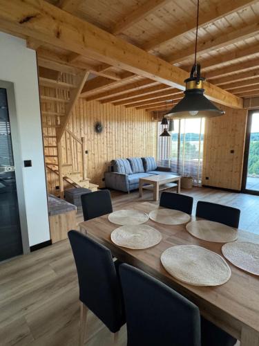 ein Esszimmer mit einem großen Holztisch und Stühlen in der Unterkunft Zajęcze Domki in Kynau
