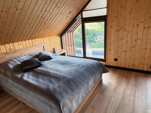 ein Schlafzimmer mit einem Bett und einem großen Fenster in der Unterkunft Zajęcze Domki in Kynau