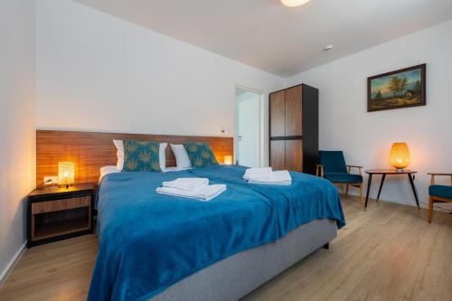 a bedroom with a blue bed with two towels on it at Apartamenty Dolina Jawornika in Wisła