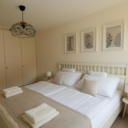 a white bedroom with a large bed with white pillows at Willkommen in Ihrem sonnigen Gartenapartment in Kitzbühel