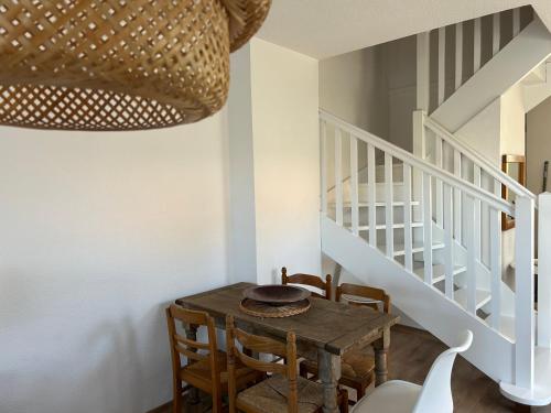 a dining room with a wooden table and stairs at Vivi in Lège-Cap-Ferret
