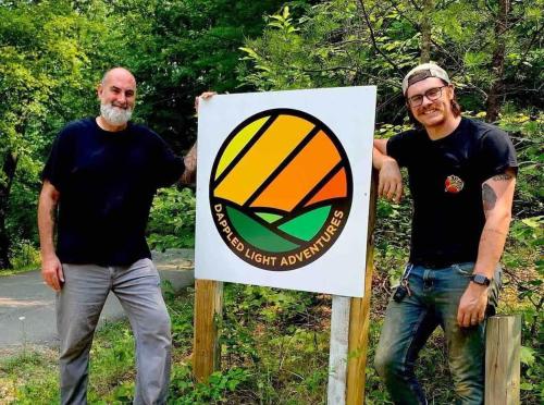 two men are standing next to a sign at The Goldfinch's Nest - Glamping Tent with AC in Rogers