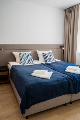 a bedroom with a large blue bed with towels on it at Apartamenty Dolina Jawornika in Wisła
