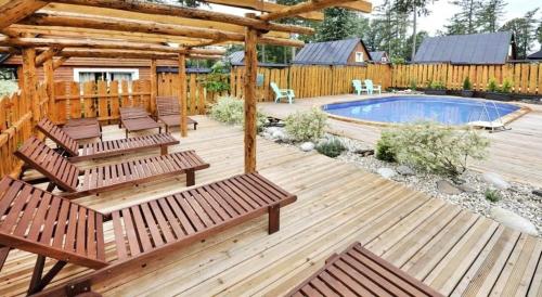 a wooden deck with benches and a swimming pool at Chata BUBO - Veľký Slavkov in Veľký Slavkov