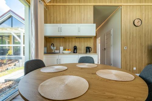 a wooden table with four chairs and a kitchen at Osada Kalwa in Tylkowo